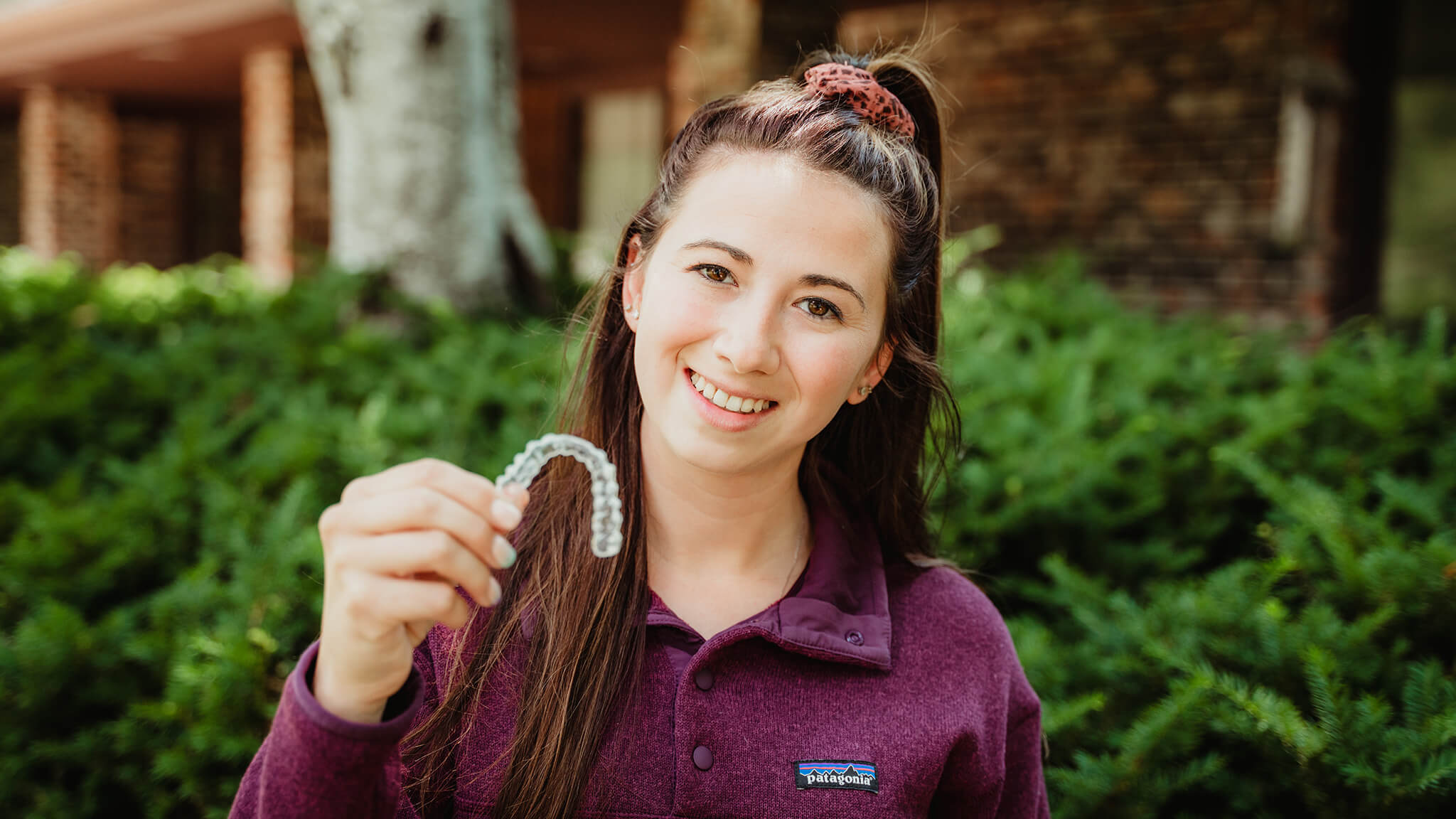 smiling woman holding aligners